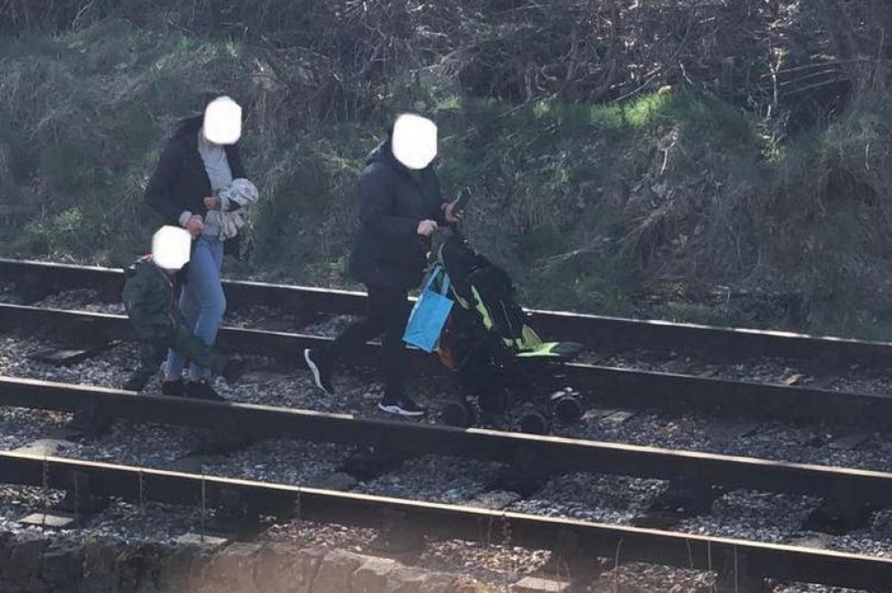 Doi tineri iresponsabili, surprinși plimbându-și copilul pe calea ferată